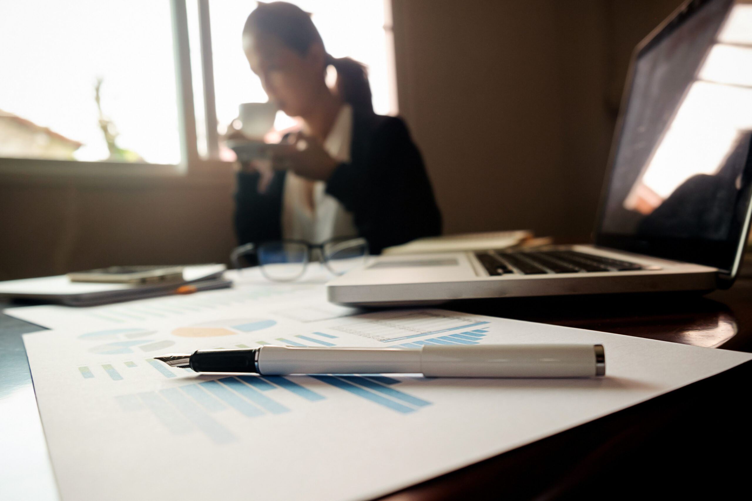 Business concept with copy space. Office desk table with pen focus and analysis chart, computer, notebook, cup of coffee on desk.Vintage tone Retro filter, selective focus.